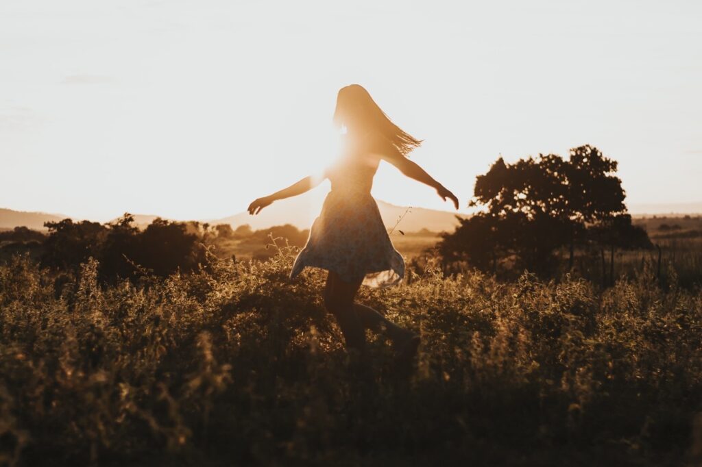 Woman outside in the sunset, looking free and relaxed.